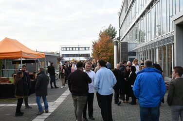 Graduates and guests stand outside in front of the faculty foyer.