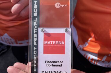 Zwei Hände halten einen Pokal aus Plexiglas mit der Aufschrift "Drachenboot Festival 2024, Phoenixsee Dortmund, Materna-Cup, A-Finale, 3. Platz".