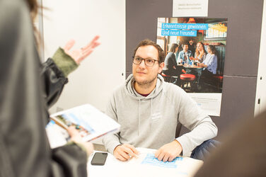 DAAD Botschafter Malte Pahlke berät eine interessierte Studentin am Messestand.DAAD Ambassador Malte Pahlke advises an interested student at the exhibition stand.