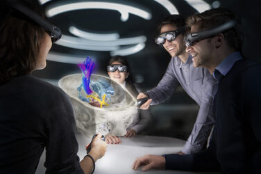 Vier junge Menschen sehen sich durch eine Virtual Reality Brille den Querschnitt eines menschlichen Schädels mit verschiedenen anatomischen Strukturen an.