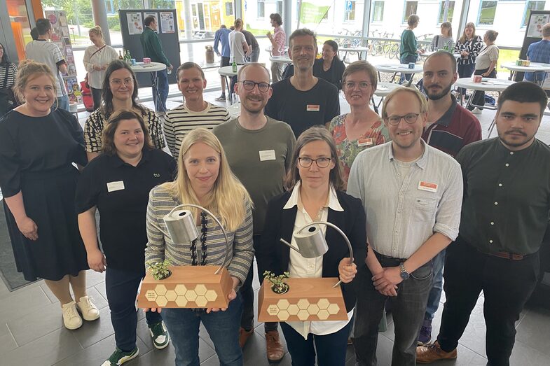 Eine Gruppe von Menschen, darunter die beiden Preisträgerinnen mit Pokalen in der Hand