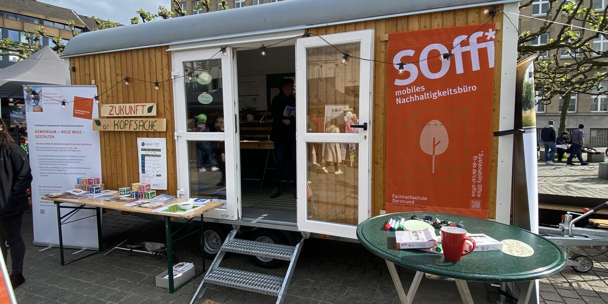 Ein umgebauter Bauwagen der nun als mobiles Nachhaltigkeitsbüro dient, steht auf einem Platz zur Ausstellung.