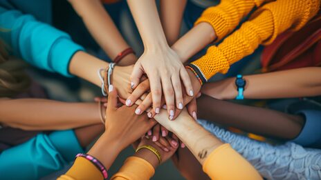 The hands of people of different skin colors touch each other.