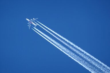 Am Himmel sind ein Flugzeug und dessen Kondensstreifen zu sehen.