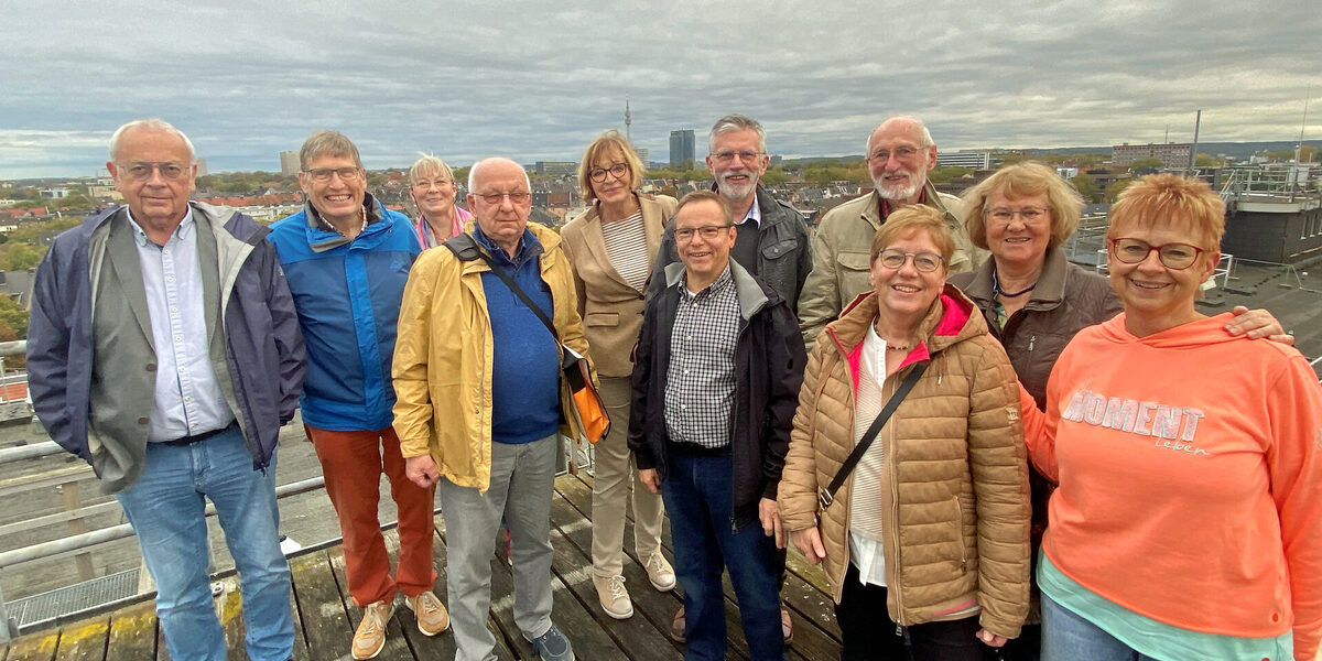 A group stands on a platform high above the rooftops of the city. The skyscrapers of Dortmund can be seen in the background.