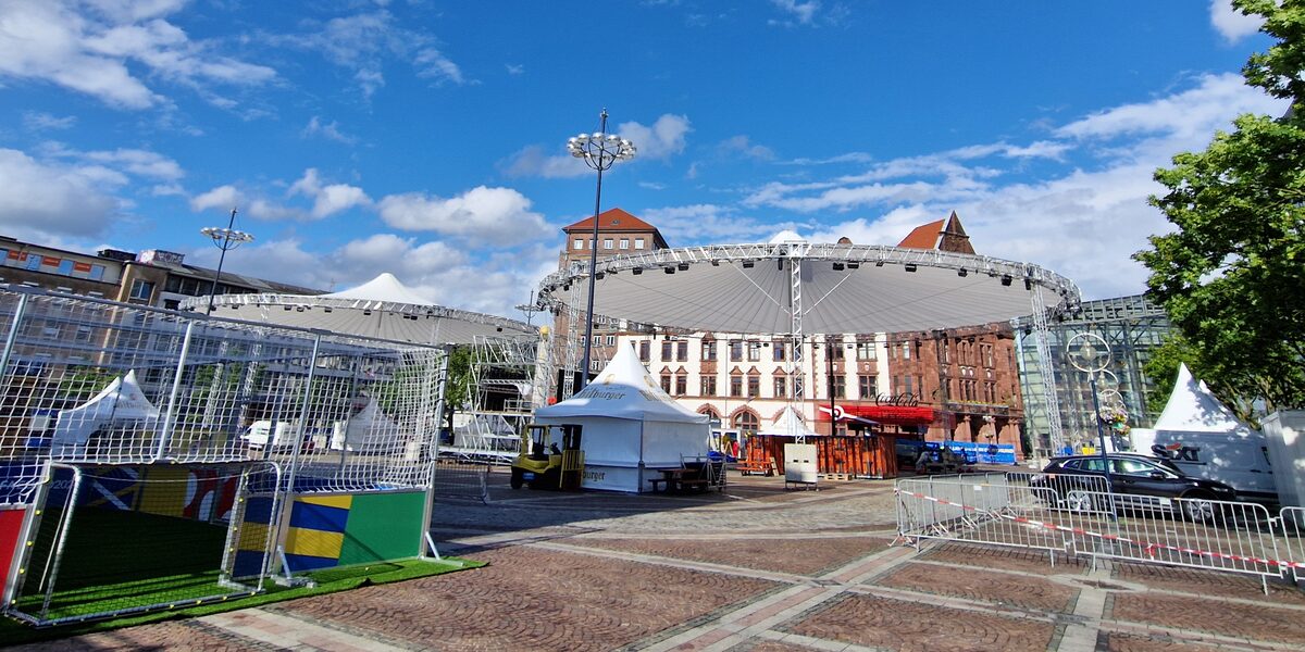 Tents, barriers and a small soccer goal are set up on a large square in front of the old Dortmund town hall.