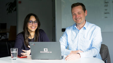 Zwei Personen sind zusammen vor einem Monitor und analysieren die Daten auf dem Bildschirm.