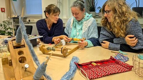 The female reader bends over a structure for weaving boards.