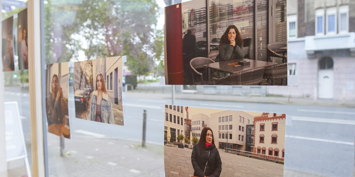 Several photos are mounted on a window pane. The photos are part of the exhibition and show the faces of refugee women who now live in Germany.