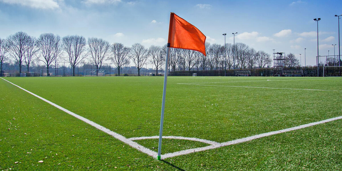 On a soccer field, a corner flag is in the foreground.