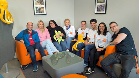 A group of people are sitting close together in the corner of a sofa.