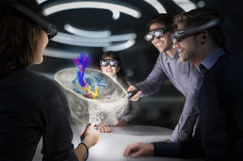 Four young people look at a cross-section of a human skull with various anatomical structures through virtual reality glasses.